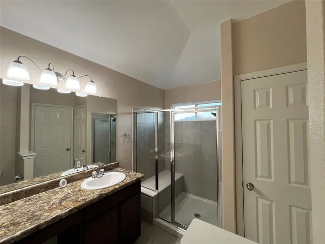 a bathroom with a granite countertop sink a toilet and shower