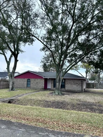 a front view of a house with a yard and large tree