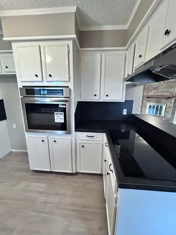 a kitchen with granite countertop white cabinets and stainless steel appliances