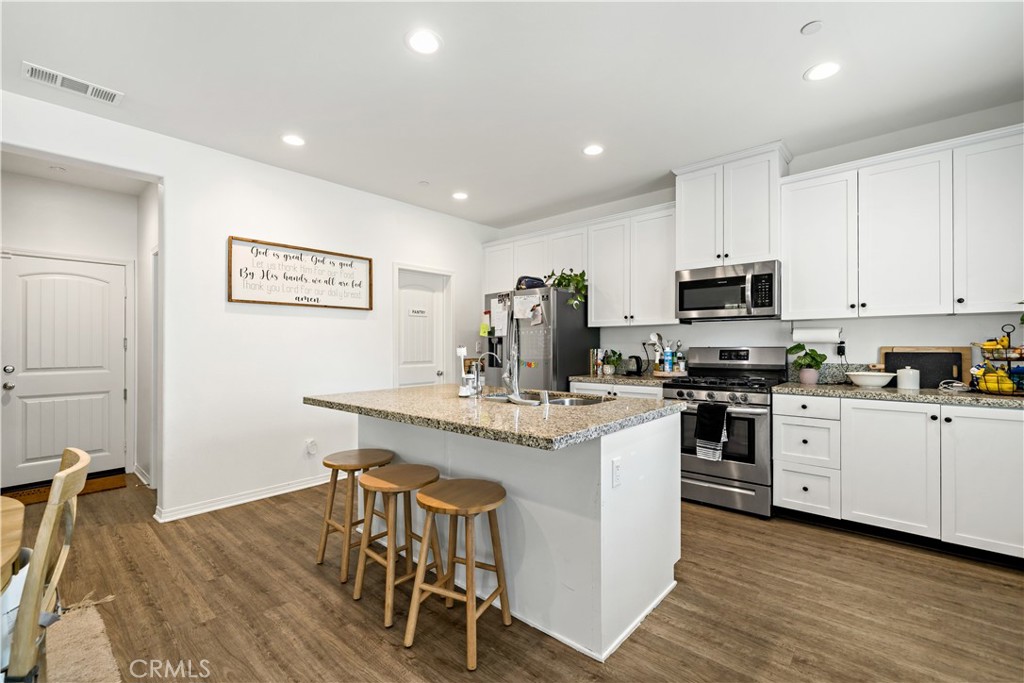30271 Ramsay Drive Menifee, CA 92584 - Photo 12 of 34 a kitchen with stainless steel appliances a white table chairs and a refrigerator