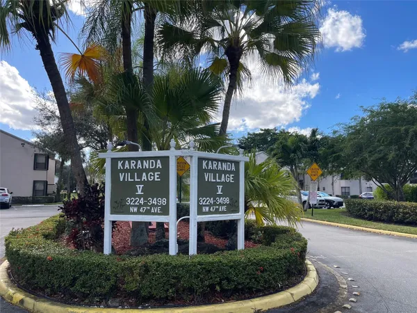 front view of house with a street sign and palm trees