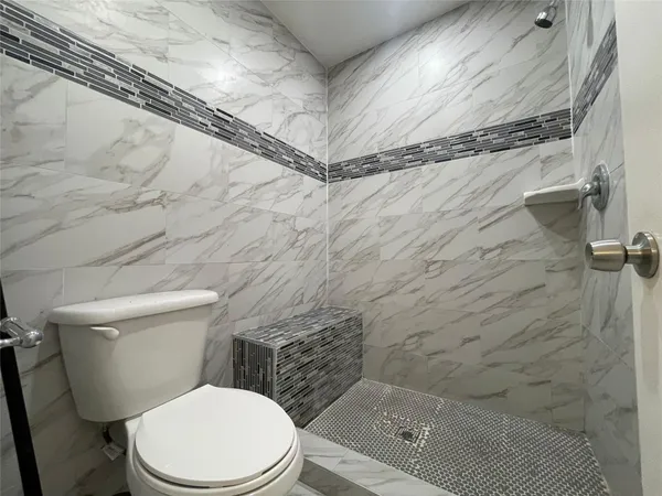 a white toilet sitting next to a shower