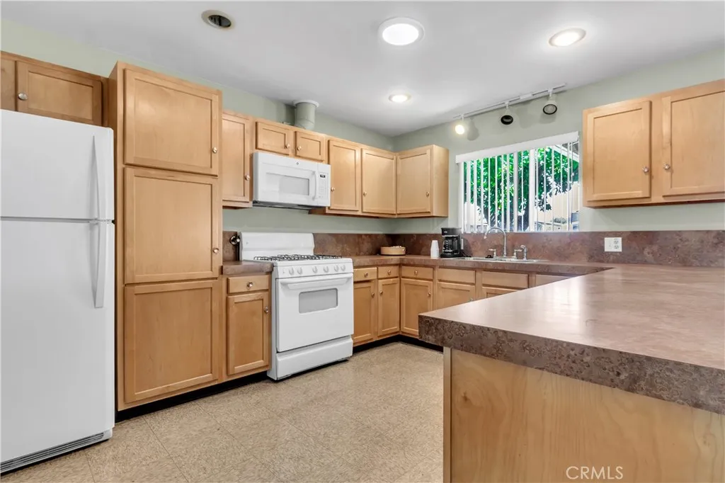 301 East Foothill Boulevard, Unit 34 Pomona, CA 91767 - Photo 15 of 35 a kitchen with granite countertop white cabinets and white appliances