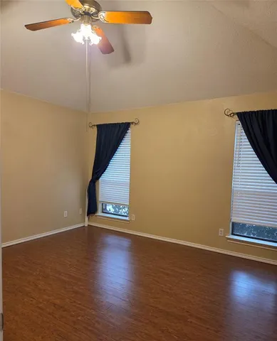 a view of an empty room and chandelier fan