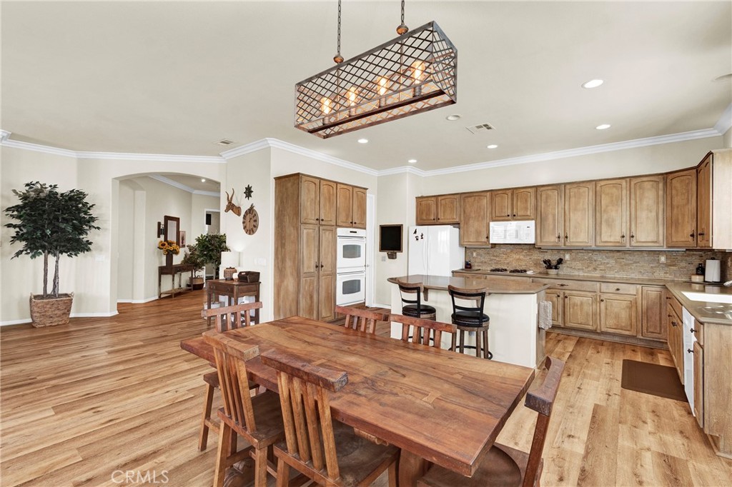 930 Gleneagles Road Beaumont, CA 92223 - Photo 14 of 40 a dining hall with stainless steel appliances kitchen island a table and chairs in it