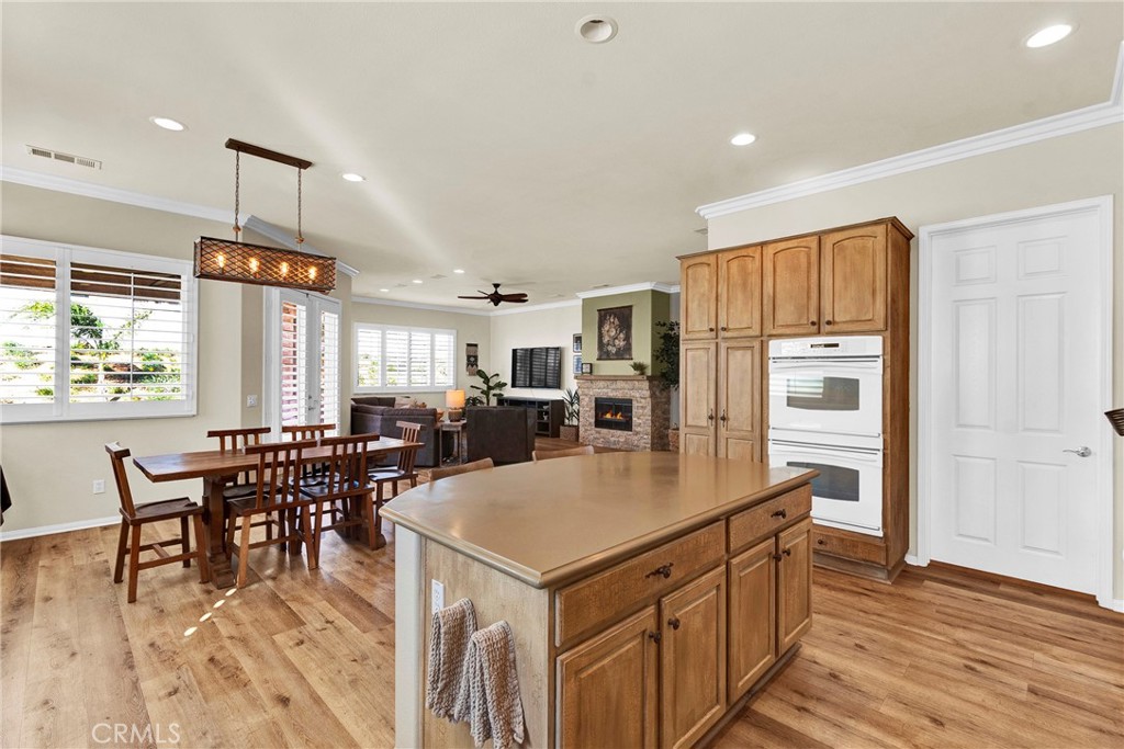 930 Gleneagles Road Beaumont, CA 92223 - Photo 16 of 40 a kitchen with stainless steel appliances granite countertop a stove a refrigerator a kitchen island a dining table and chairs with wooden floor