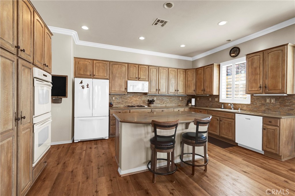 930 Gleneagles Road Beaumont, CA 92223 - Photo 17 of 40 a kitchen with a refrigerator a white stove top oven a sink with island and chairs