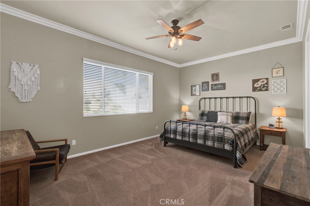 930 Gleneagles Road Beaumont, CA 92223 - Photo 19 of 40 a spacious bedroom with a bed and a chandelier