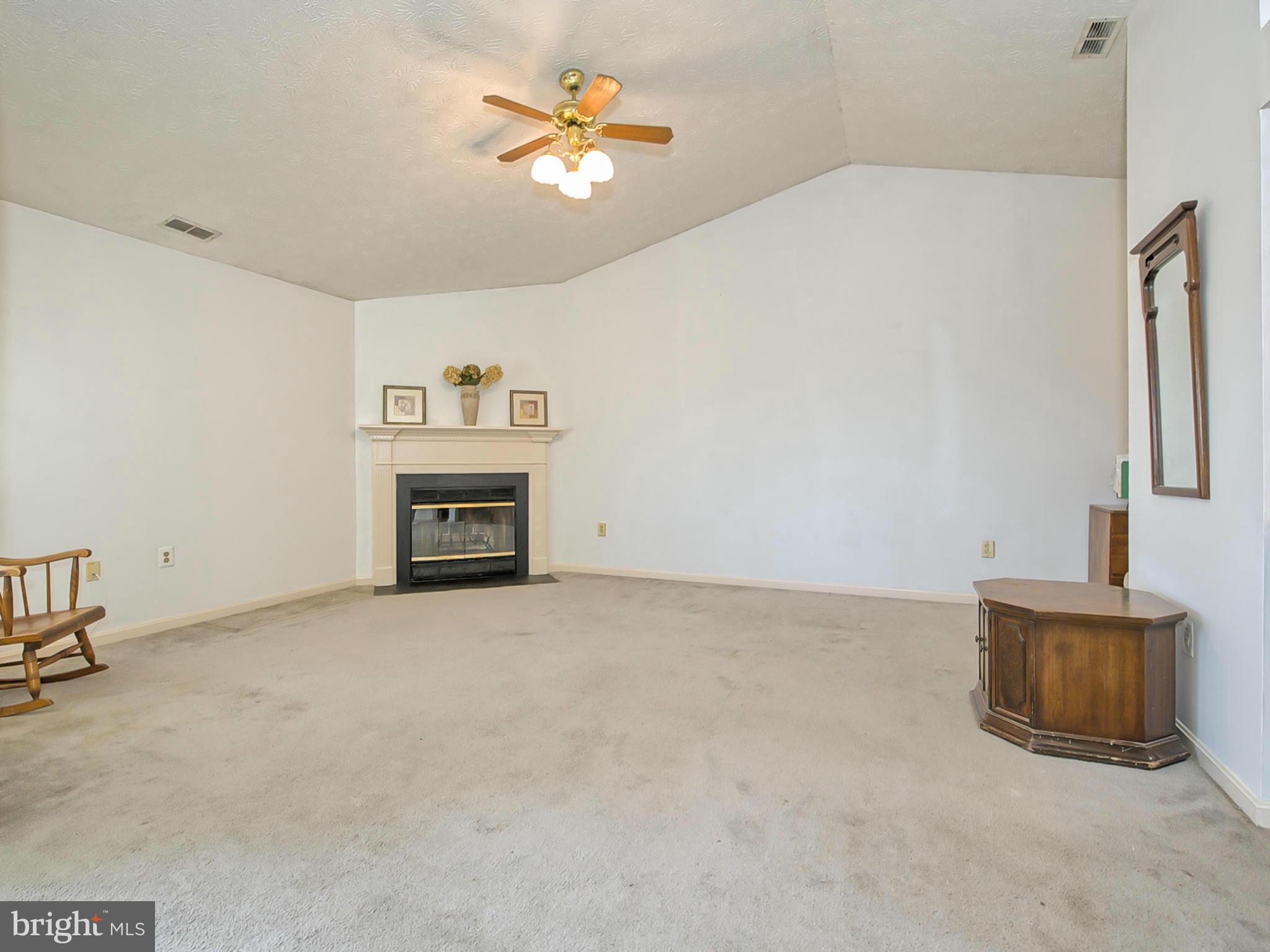 2137 Wainwright Court, Unit 2B Frederick, MD 21702 - Photo 11 of 30 an empty room with a fireplace and a chandelier fan