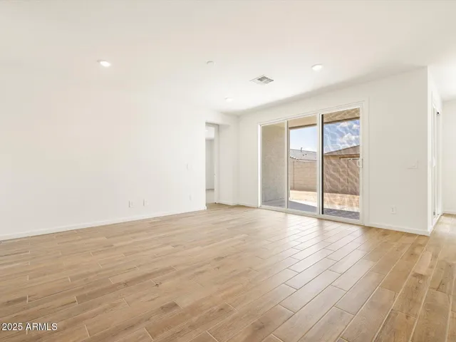a view of an empty room with wooden floor and windows