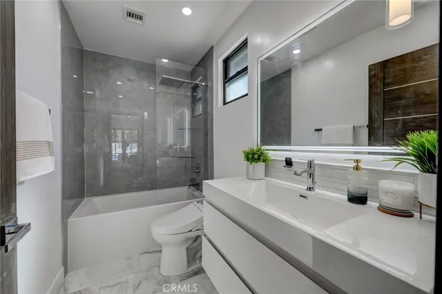 a bathroom with a bathtub shower sink vanity and toilet