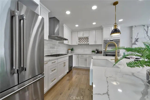 a kitchen with stainless steel appliances granite countertop a refrigerator a sink dishwasher a oven and white cabinets with wooden floor