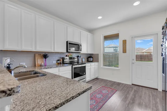 a kitchen with granite countertop a stove a sink and a microwave
