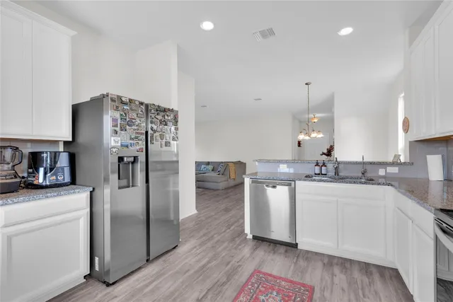 a kitchen with stainless steel appliances a sink a stove a refrigerator and cabinets