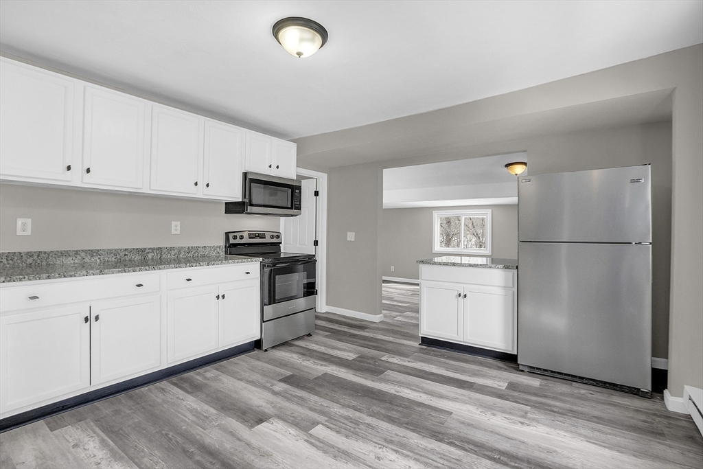 73 Ash Street Gardner, MA 01440 - Photo 3 of 40 a kitchen with granite countertop a refrigerator stove and white cabinets