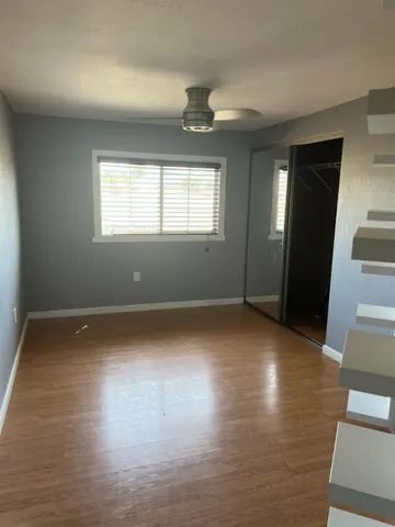 an empty room with wooden floor and windows