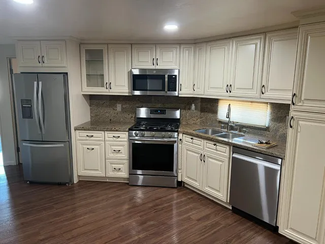 a kitchen with granite countertop white cabinets and stainless steel appliances