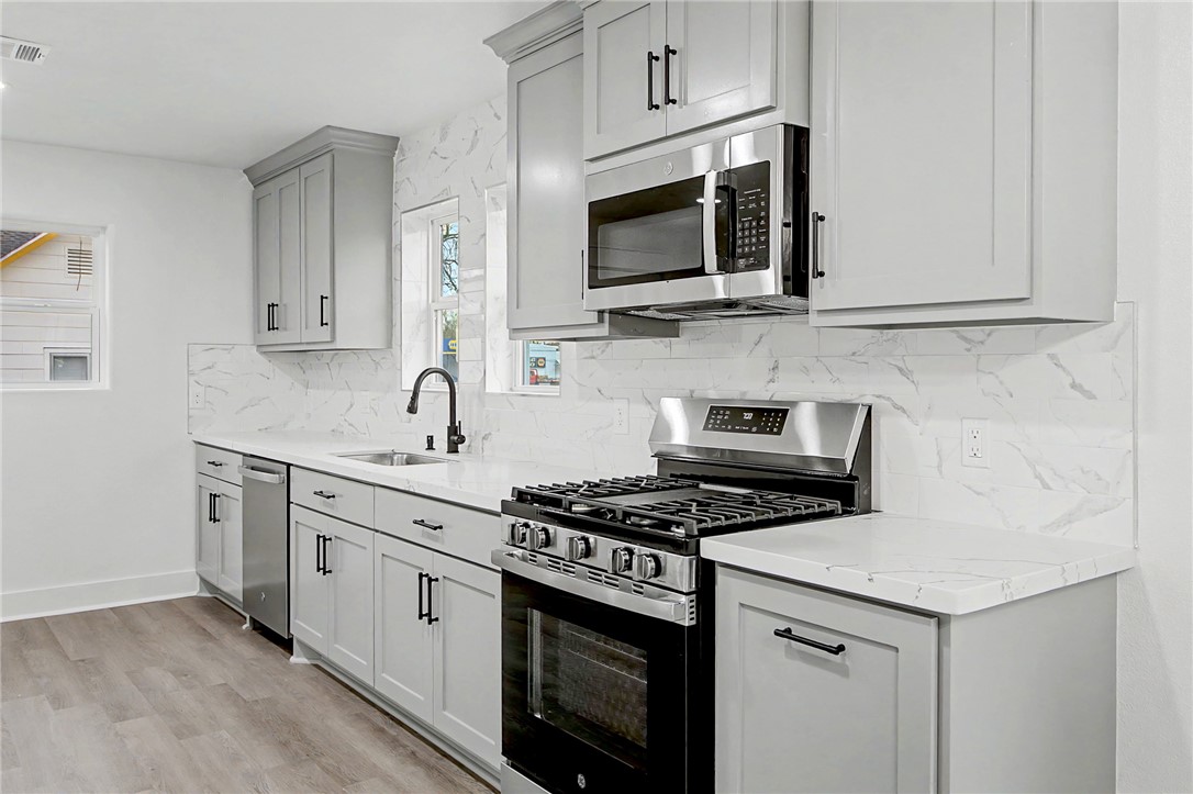 902 Post Oak Street Hearne, TX 77859 - Photo 11 of 26 a kitchen with stainless steel appliances granite countertop grey cabinets a stove a sink and a microwave