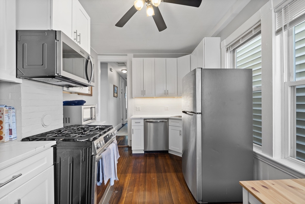 194 Emerson Street Boston, MA 02127 - Photo 5 of 18 a kitchen with stainless steel appliances granite countertop a refrigerator a sink dishwasher a stove and a dining table with wooden floor