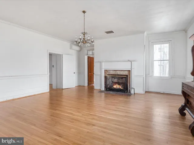 a view of a livingroom with a fireplace a chandelier and wooden floor