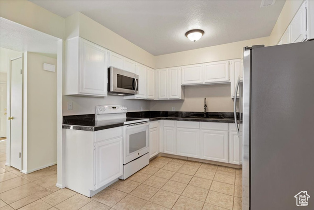 947 Canyon Road South, Unit 15 Ogden, UT 84404 - Photo 10 of 22 Kitchen with appliances with stainless steel finishes, white cabinetry, light tile patterned floors, and tile counters