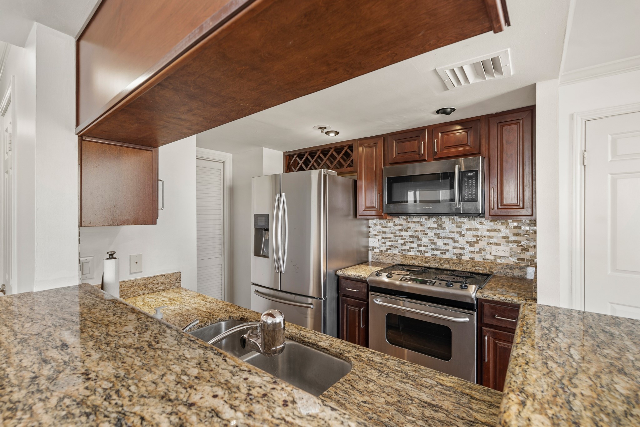 3525 Sage Road, Unit 1204 Houston, TX 77056 - Photo 13 of 25 Kitchen with granite counters, upper and lower cabinetry, and built-in appliances.