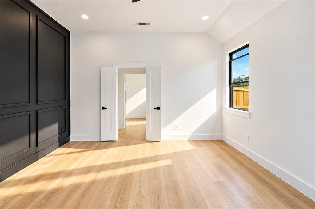 1640 West Wintergreen Road Lancaster, TX 75134 - Photo 17 of 37 Wood-finish flooring, recessed lighting, accent wall with panel molding, black-framed window with wood fence backdrop, and double doors with black hardware
