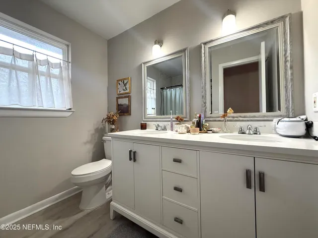 a bathroom with a toilet a sink a mirror and a window