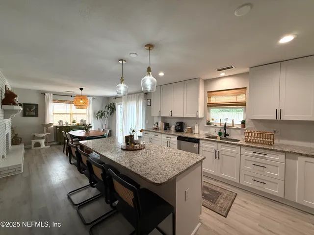 a kitchen with granite countertop a stove a sink a dining table and chairs with wooden floor