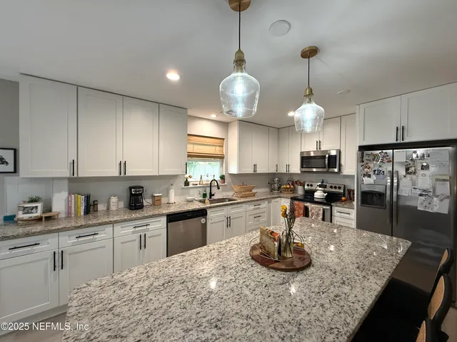 a kitchen with stainless steel appliances granite countertop a sink a stove and chairs
