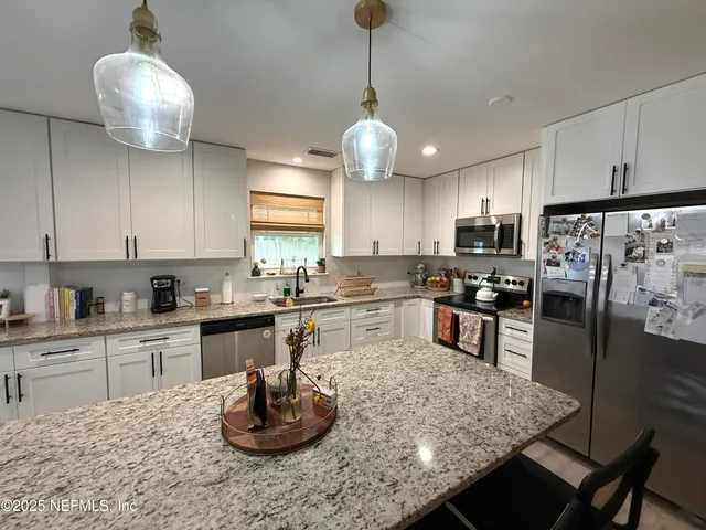 a kitchen with stainless steel appliances granite countertop a sink refrigerator and cabinets