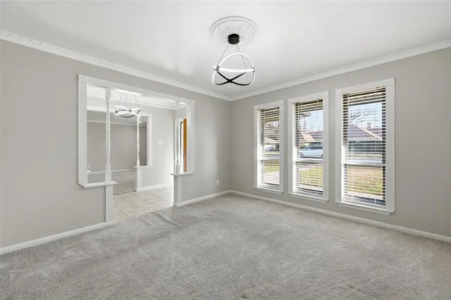 an empty room with windows and chandelier fan