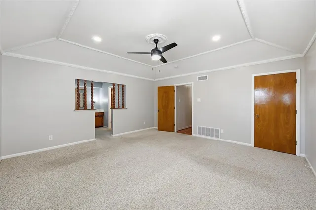 an empty room with chandelier fan and windows