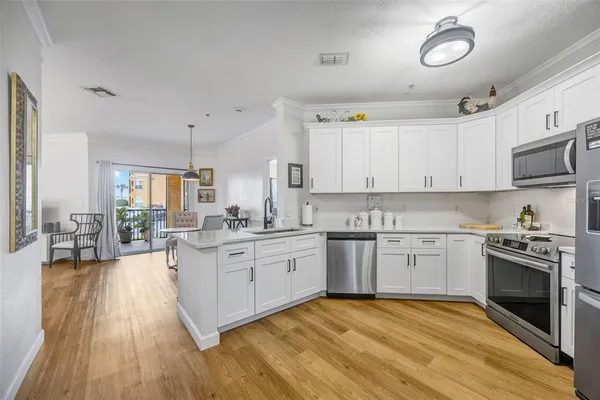 a kitchen with stainless steel appliances granite countertop a refrigerator stove a sink and white cabinets with wooden floor