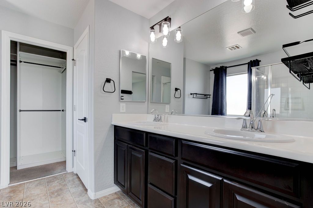 7724 Vibrant Thread Court Las Vegas, NV 89149 - Photo 24 of 43 A sleek vanity with dual sinks, set against light walls, provides ample space.