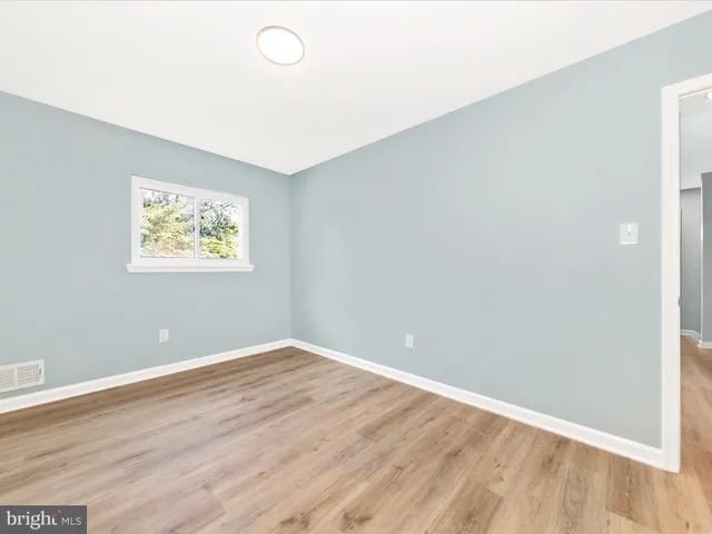 an empty room with wooden floor and window