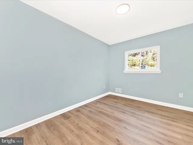 an empty room with wooden floor and window