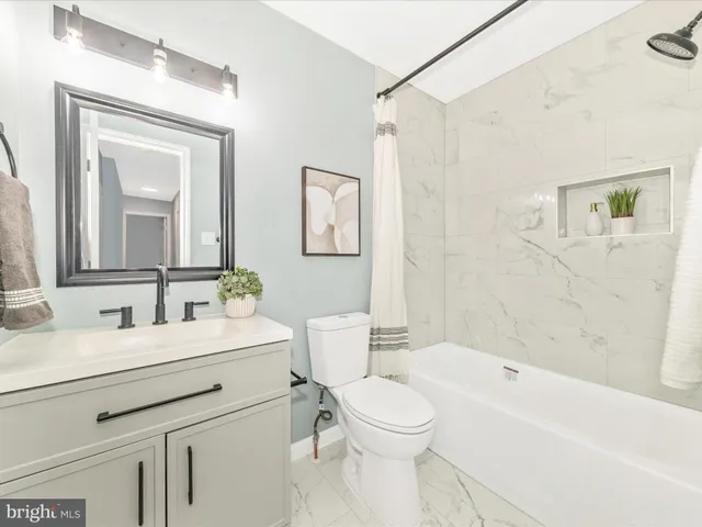 a bathroom with a toilet a sink a mirror a bathtub and a vanity