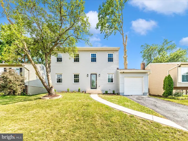 a view of a white house with a large tree and a yard in front of it