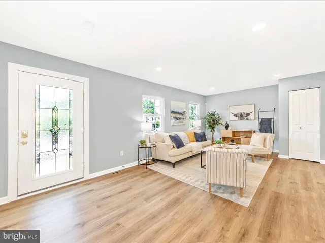 a living room with furniture large window and wooden floor
