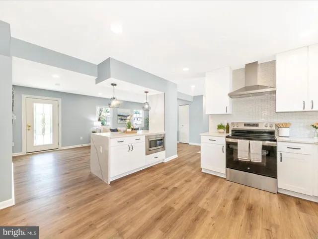 a kitchen with stainless steel appliances white cabinets a wooden floor and a sink