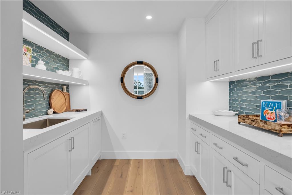 13945 Old Coast Road, Unit 301 Naples, FL 34110 - Photo 14 of 30 a kitchen with white cabinets and a wooden floor