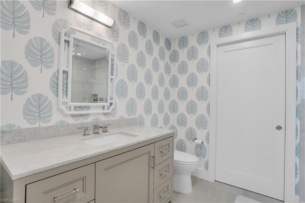 13945 Old Coast Road, Unit 301 Naples, FL 34110 - Photo 18 of 30 a bathroom with a granite countertop sink a toilet and a mirror