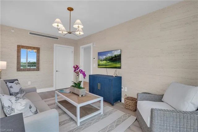 a living room with furniture a chandelier and a flat screen tv