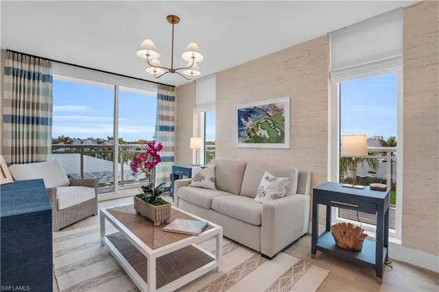 a living room with furniture a chandelier and a large window