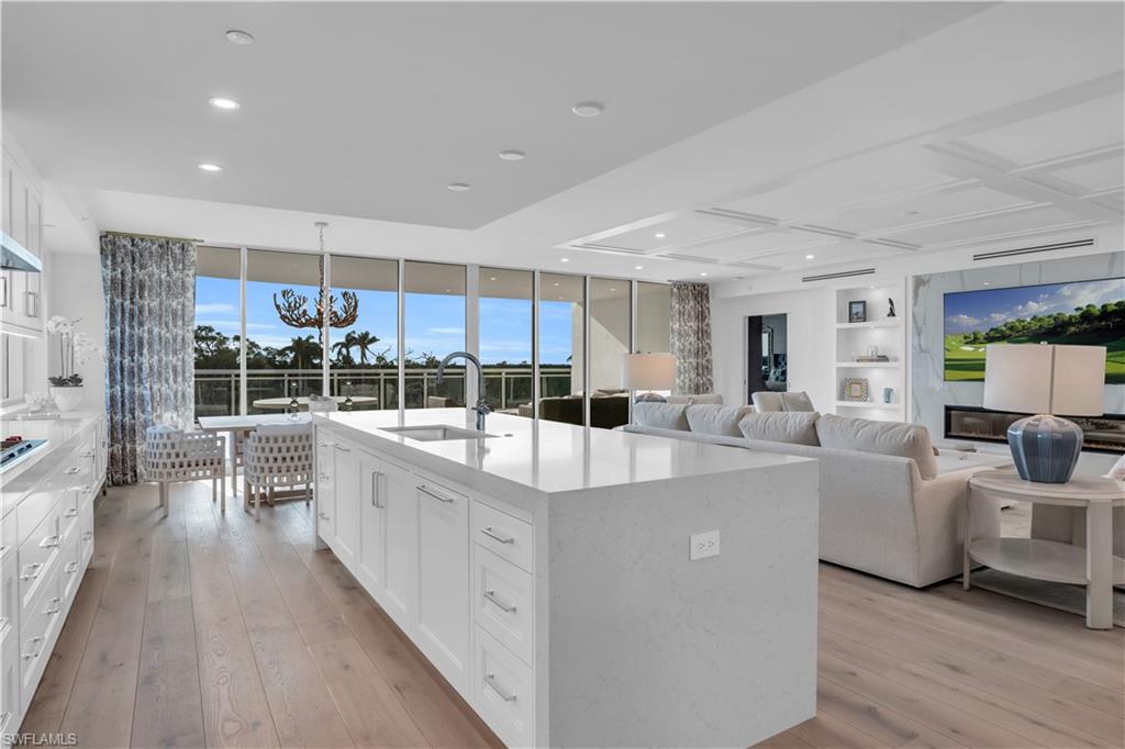 13945 Old Coast Road, Unit 301 Naples, FL 34110 - Photo 3 of 30 a large white kitchen with sink and wooden floor