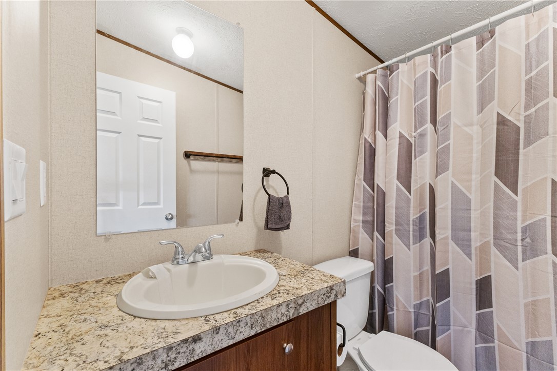 1014 Doe Run Road Caldwell, TX 77836 - Photo 20 of 23 a bathroom with a granite countertop sink and a mirror