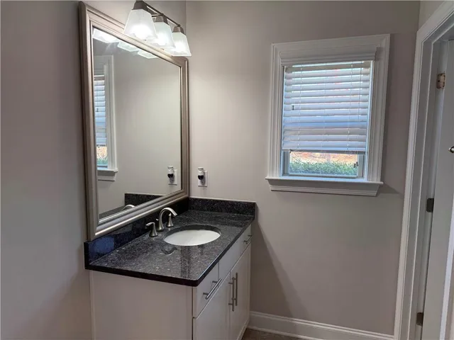 a bathroom with a granite countertop sink and a mirror