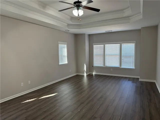 an empty room with wooden floor chandelier fan and windows