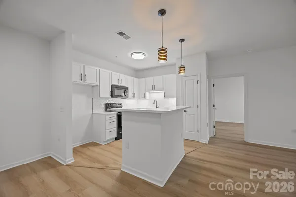 a kitchen with cabinets stainless steel appliances a sink and wooden floor